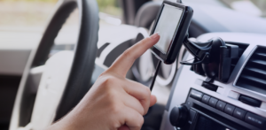 Close-up of a hand interacting with a GPS navigation device mounted on a car dashboard
