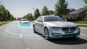 Two cars travel along a suburban road with a graphic illustrating vehicle safety sensors detecting the car behind