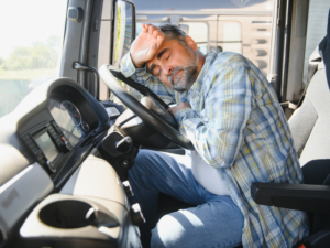 Exhausted truck driver resting his head on the steering wheel, showing signs of fatigue