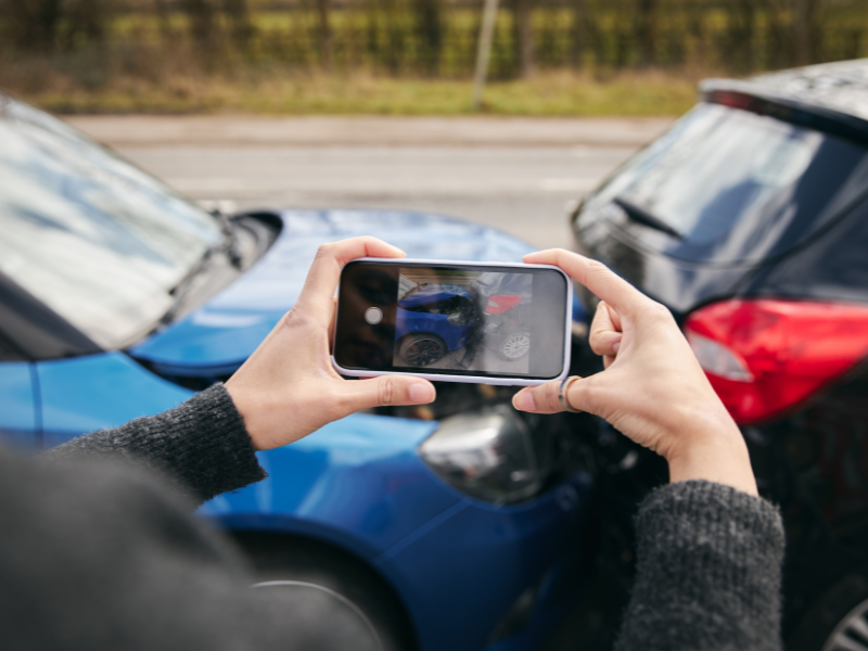 Person takes photo of car crash damage between two vehicles for insurance evidence
