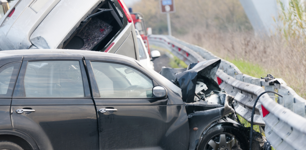 Damaged car crashed into guardrail with crushed front end, depicting a serious road traffic accident scene