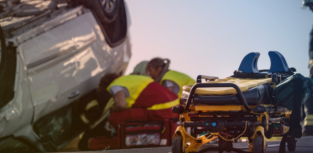 Ambulance stretcher stands ready as emergency responders assist at an overturned vehicle crash