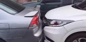 Front of a white car pressed against the rear of a silver sedan after a rear-end collision