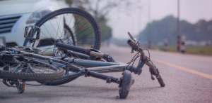 Damaged bicycle lies on its side in the roadway near the front of a vehicle
