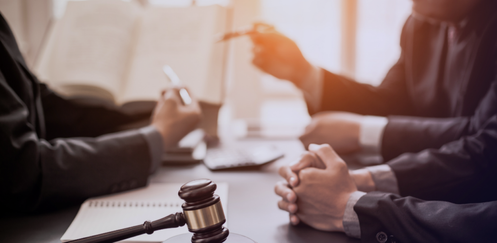 Gavel in the foreground as legal professionals discuss documents around a table